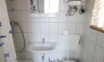 linke Hälfte vom Doppelbungalow zum Gehweg hin mit Terrasse, Bad mit Dusche und WC, Schlafzimmer mit Doppelbett und Doppelstockbett, Wohnzimmer mit Couch und Fernseher sowie eine kleine Pantry Küche